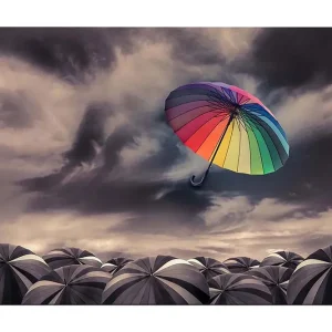 Rabatter Canvastavla 70x100 cm - Färgglad paraply svävar över en samling gråa paraplyer under ett dramatiskt molnigt himmel Regnbågsfärger / Grå - Inredning