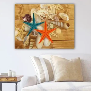 Beställ idag Canvastavla 70x100 cm - Två färgglada sjöstjärnor i orange och turkos bland snäckor på en träyta Turkos / Orange / Beige - Inredning