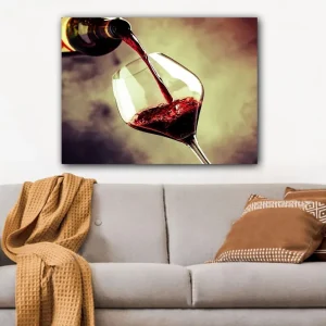 Premium Canvastavla 70x100 cm - Vinflaska hälls i ett glas med rödvin som skapar en elegant och inbjudande atmosfär Röd / Grön / Gul - Inredning
