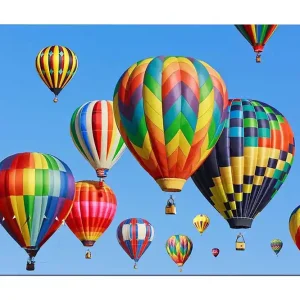 Rabatter Canvastavla 70x100 cm - Flera färgglada varmluftsballonger sväva i en klar blå himmel Röd / Grön / Gul - Inredning