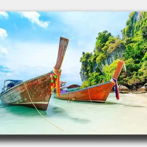 Canvastavla 70x100 cm - Två traditionella thailändska långbåtar vid en strand med klippor och grönskande vegetation i bakgrunden Brun / Grön / Blå - Inredning Premium